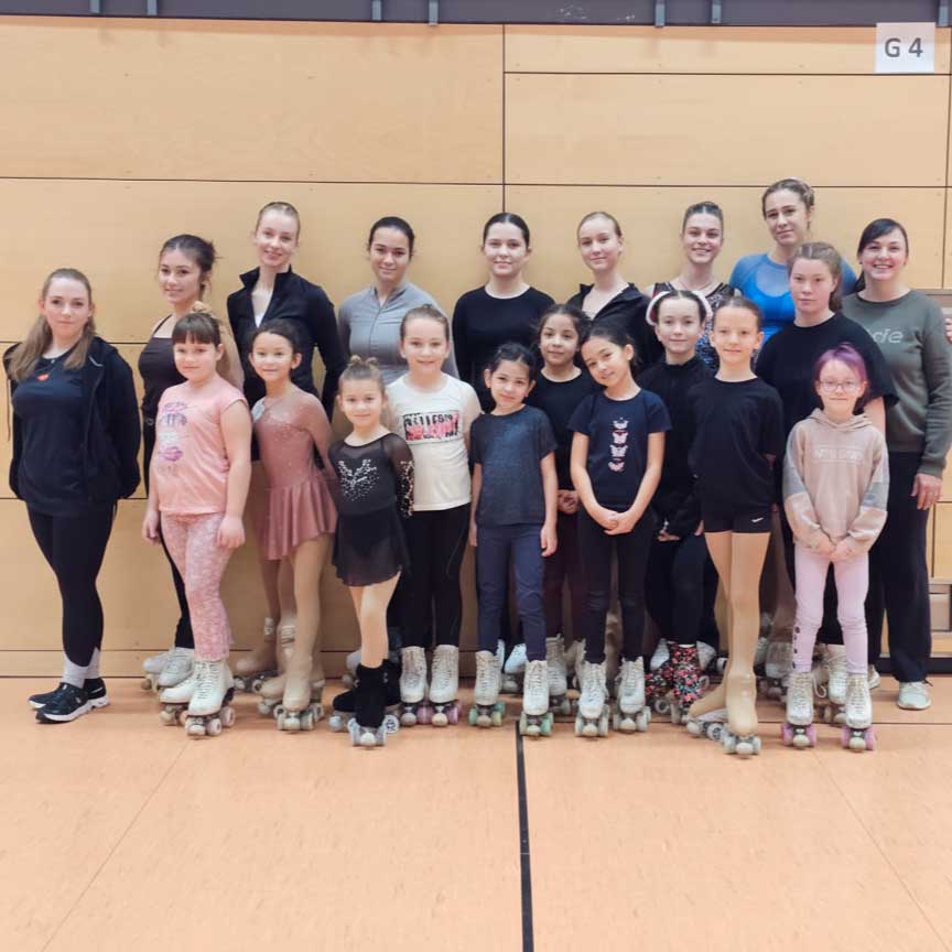 Gruppenfoto von jungen Rollkunstläuferinnen und -läufern des Verein BTV 1846 in Wuppertal auf Rollschuhen in einer Sporthalle.